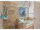 Luxurious shower and tub combo with travertine tile, seamless glass and neutral tones at 7539 W Kimberly Way, Glendale, AZ 85308