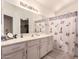 Bathroom featuring a single sink vanity, large mirror, and a shower-tub combo with decorative shower curtain at 8947 W Sierra Vista Dr, Glendale, AZ 85305