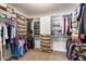A spacious walk in closet has rows of hanging clothes, shelves of shoes, and a neutral colored carpet at 8960 W Kerry Ln, Peoria, AZ 85382