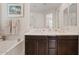 Bright bathroom featuring separate tub, double vanity, and dark wood cabinets at 9910 E Theia Dr, Mesa, AZ 85212