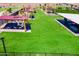 Aerial view of an outdoor community recreation area featuring shade structures, tables, and fire pits on lush green grass at 12219 E Sunflower Ln, Florence, AZ 85132