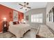 Bedroom with orange accent wall, ceiling fan, and a white shuttered window at 1240 E Friess Dr, Phoenix, AZ 85022