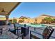 Covered patio with a view of the pool with a rock waterfall, surrounded by desert landscaping and outdoor furniture at 12814 W Windrose Dr, El Mirage, AZ 85335