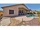 View of the backyard with a private pool, covered patio seating area, desert landscaping, and stone pathway at 12814 W Windrose Dr, El Mirage, AZ 85335