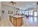 Open-concept kitchen with stainless steel appliances, wooden cabinets, island with seating, and adjacent dining area at 12814 W Windrose Dr, El Mirage, AZ 85335