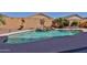 Private backyard pool with a rock waterfall, desert landscaping, and a partially visible pool cleaning hose at 12814 W Windrose Dr, El Mirage, AZ 85335