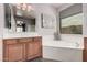 Bathroom featuring wood cabinets, double sink vanity, soaker tub, and modern decor at 1446 E Canary Dr, Gilbert, AZ 85297