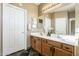 Bathroom with double sinks, white countertops and wood cabinets, with a large mirror above the vanity at 14837 W Crocus Dr, Surprise, AZ 85379