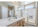 Well-lit bathroom with a double vanity, glass-enclosed shower, and neutral color palette providing a clean and modern space at 14837 W Crocus Dr, Surprise, AZ 85379