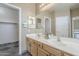 Bathroom featuring double sinks, vanity with wooden cabinets, a large mirror, and tile flooring, leading to a walk-in closet at 14837 W Crocus Dr, Surprise, AZ 85379