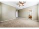 This bedroom has neutral carpet and paint, a ceiling fan, and an ensuite bathroom at 14837 W Crocus Dr, Surprise, AZ 85379