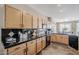 Kitchen featuring wood cabinets, black countertops, black appliances and a black tile backsplash providing a functional cooking area at 14837 W Crocus Dr, Surprise, AZ 85379