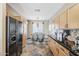 Spacious kitchen features wooden cabinets, black appliances, and tile flooring, flowing into a dining area with natural light at 14837 W Crocus Dr, Surprise, AZ 85379