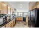 Bright kitchen showcasing wood cabinets, black appliances, and black countertops with an adjacent dining space and living area at 14837 W Crocus Dr, Surprise, AZ 85379