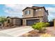 This two-story home features neutral stucco siding, a tile roof, dark garage door, and desert landscaping in the front yard at 1525 W Bent Tree Dr, Phoenix, AZ 85085