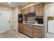 A functional kitchen area with wooden cabinets, essential appliances, and convenient access to a laundry room at 15621 N Lakeforest Dr, Sun City, AZ 85351