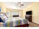 Well-lit bedroom featuring a large bed, wood floors, ceiling fan, and shuttered windows at 17203 E Starflower Ct, Queen Creek, AZ 85142