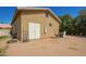 A beige building with a white, double door, and an air conditioning unit sits in a sunny, rural outdoor space at 17203 E Starflower Ct, Queen Creek, AZ 85142