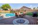 Backyard with a dining table, fire pit, well-manicured landscape, and a refreshing pool at 17423 W Yavapai St, Goodyear, AZ 85338