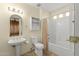 Clean bathroom features a pedestal sink, white toilet, built in shelves, and shower and tub combination with shower curtain at 17882 N Painted Spurge Ct, Surprise, AZ 85374