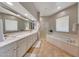 Bright bathroom with double vanity, framed mirrors, soaking tub, and glass shower at 20802 N Grayhawk Dr # 1017, Scottsdale, AZ 85255