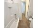 Bright bathroom with a white tiled tub-shower and wood-look flooring extending to the toilet and doorway at 25912 N Langley Dr, Peoria, AZ 85383