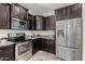 Kitchen featuring stainless steel appliances and dark wood cabinets with granite countertops and tiled floor at 25983 W Escuda Dr, Buckeye, AZ 85396