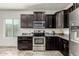 Kitchen with stainless steel appliances, dark wood cabinets and drawers, granite countertops, and tile flooring at 25983 W Escuda Dr, Buckeye, AZ 85396