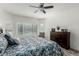 Well-lit main bedroom featuring tiled floors, ceiling fan, large windows, and dresser at 25983 W Escuda Dr, Buckeye, AZ 85396