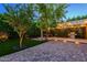 Expansive backyard featuring a stone paver patio, pergola with string lights, vibrant trees, and a built-in grill at 29219 W Clarendon Ave, Buckeye, AZ 85396