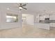 Bright living room with neutral tile flooring, ceiling fan, and adjacent kitchen area at 3903 E French Trotter St, San Tan Valley, AZ 85140