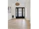 Bright entryway featuring modern light fixture, light wood floors, and unique black doors to welcome guests at 5819 E Ludlow Dr, Scottsdale, AZ 85254