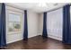 A bright bedroom features hardwood floors and windows with dark-blue and sheer white curtains at 919 S Pheasant Dr, Gilbert, AZ 85296