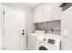 Well-lit laundry room featuring white cabinets, shelving, and modern appliances including a washer and dryer at 930 W Hudson Way, Gilbert, AZ 85233