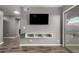 Minimalist living area features a mounted television above a white floating storage unit with adjacent sliding glass door at 930 W Hudson Way, Gilbert, AZ 85233