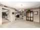 Open living area featuring plush carpeting, chandelier lighting, and seamless access to the adjacent kitchen at 9946 W Willow Creek Cir, Sun City, AZ 85373