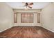 Comfortable bedroom with wood floors, a ceiling fan, and ample natural light through shuttered windows at 12852 W El Sueno Dr, Sun City West, AZ 85375