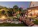 Landscaped backyard showcasing lush greenery, a charming wooden bridge, and a covered patio seating area at 12955 E Mercer Ln, Scottsdale, AZ 85259