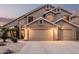 Inviting two-story home with a three-car garage, desert landscaping, and a warm, welcoming glow at dusk at 12955 E Mercer Ln, Scottsdale, AZ 85259