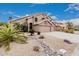 Desert landscaping including rocks, gravel, and palm trees accent this home with a three car garage at 12955 E Mercer Ln, Scottsdale, AZ 85259