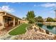 Landscaped backyard features a lush lawn, rock garden, covered patio, and scenic lake views at 1453 E Butler Cir, Chandler, AZ 85225