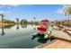 Dock with pontoon boat on a calm lake, surrounded by well-maintained houses and palm trees at 1453 E Butler Cir, Chandler, AZ 85225