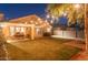 Backyard with a covered patio and string lights illuminating the landscaped lawn and fire pit at 16634 N 33Rd Way, Phoenix, AZ 85032