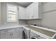 Laundry room featuring overhead cabinets, counter, and modern washer and dryer at 16945 W Vernon Ave, Goodyear, AZ 85395