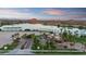 An aerial view of a commercial building and parking lot surrounded by a lake with palm trees and desert mountains at 18178 W Desert View Ln, Goodyear, AZ 85338