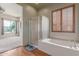 Bright bathroom featuring a glass shower, soaking tub, and window with wooden blinds at 18178 W Desert View Ln, Goodyear, AZ 85338
