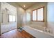 Bright bathroom featuring a soaking tub, glass-enclosed shower, and wood-look flooring at 18178 W Desert View Ln, Goodyear, AZ 85338