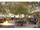 Inviting outdoor dining area with a fire pit, surrounded by trees and patrons enjoying meals at 18178 W Desert View Ln, Goodyear, AZ 85338