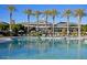 A large pool with palm trees, lounge chairs, and umbrellas with buildings in the background on a sunny day at 18178 W Desert View Ln, Goodyear, AZ 85338