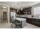 Well-lit kitchen featuring stainless steel appliances, dark wood cabinetry, and a central island with barstool seating at 18436 E Celtic Manor Dr, Queen Creek, AZ 85142